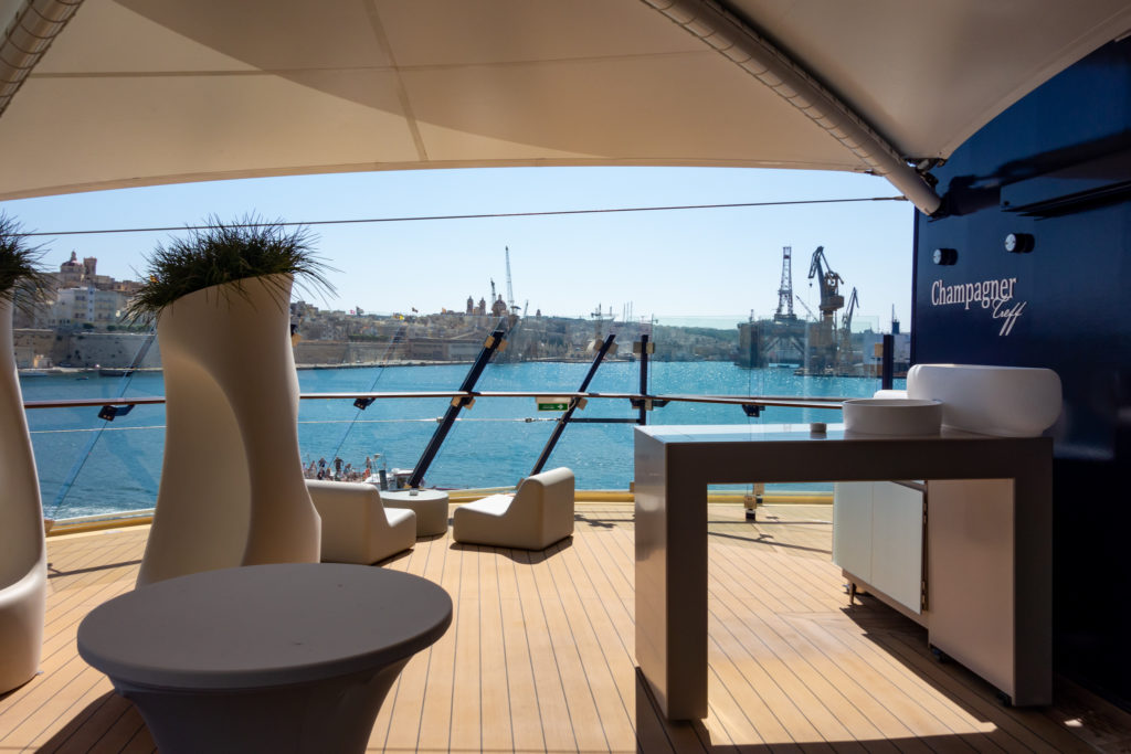 Der Champagnertreff an Bord der Mein Schiff 3, im Hintergrund ist der Hafen von Valetta zu sehen. Es ist schönes, sonniges Wetter.