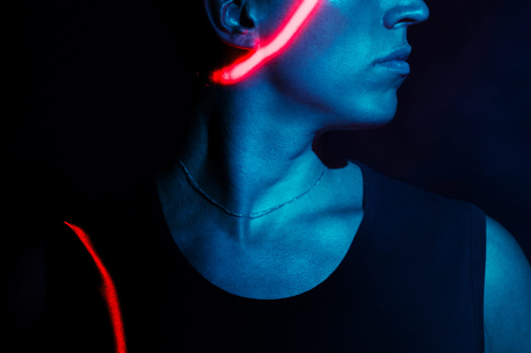 Martin Kohlstedt. Es ist ein Profilfoto, er trägt ein schwarzes Muskel-Shirt, er ist durch das Licht in blau getaucht und über seinem Kopf ist ein Teil eines roten Rings aus Licht zu sehen.