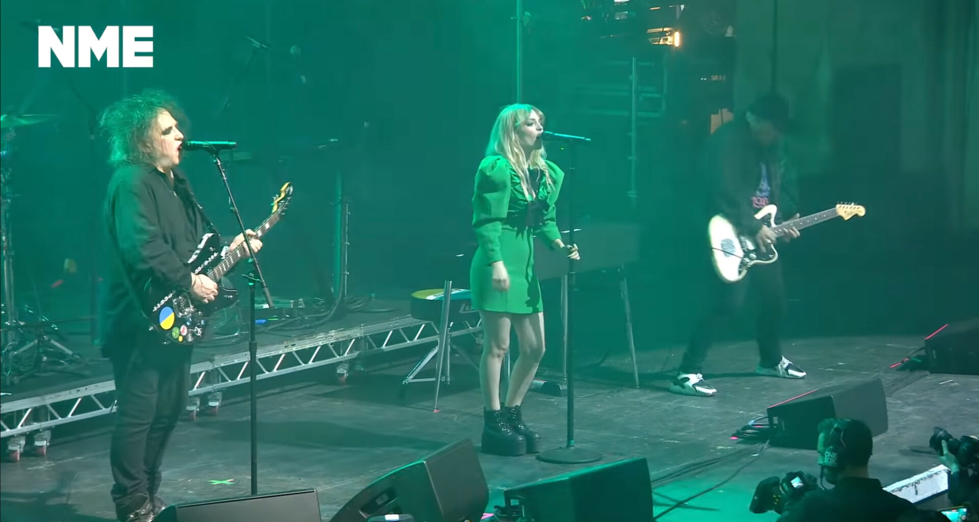 Lauren Mayberry und Robert Smith stehen gemeinsam auf der Bühne und tragen How Not To Drown vor. Lauren trägt ein grünes Kleid, ebenso ist die Bühne in grünes Licht getaucht.