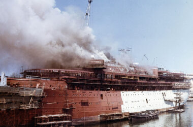 Die sich im Bau befindliche Achille Lauro.Ein Feuer ist an Bord ausgebrochen und dicke Rauchschwaden steigen aus dem Schiff empor.